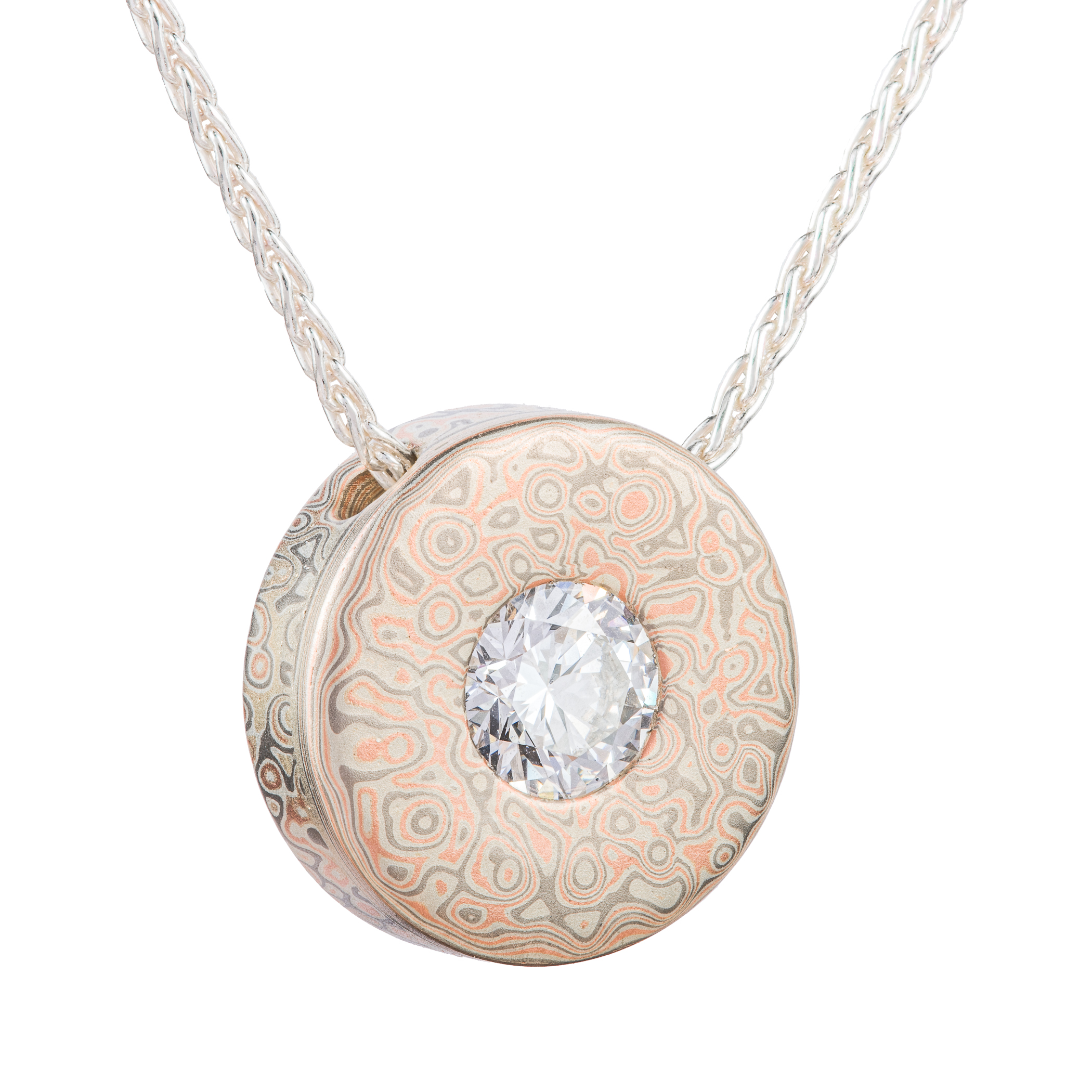 Small round pendant with a moissanite set in the center on a chain, patterned in a style that looks like raindrops on water.