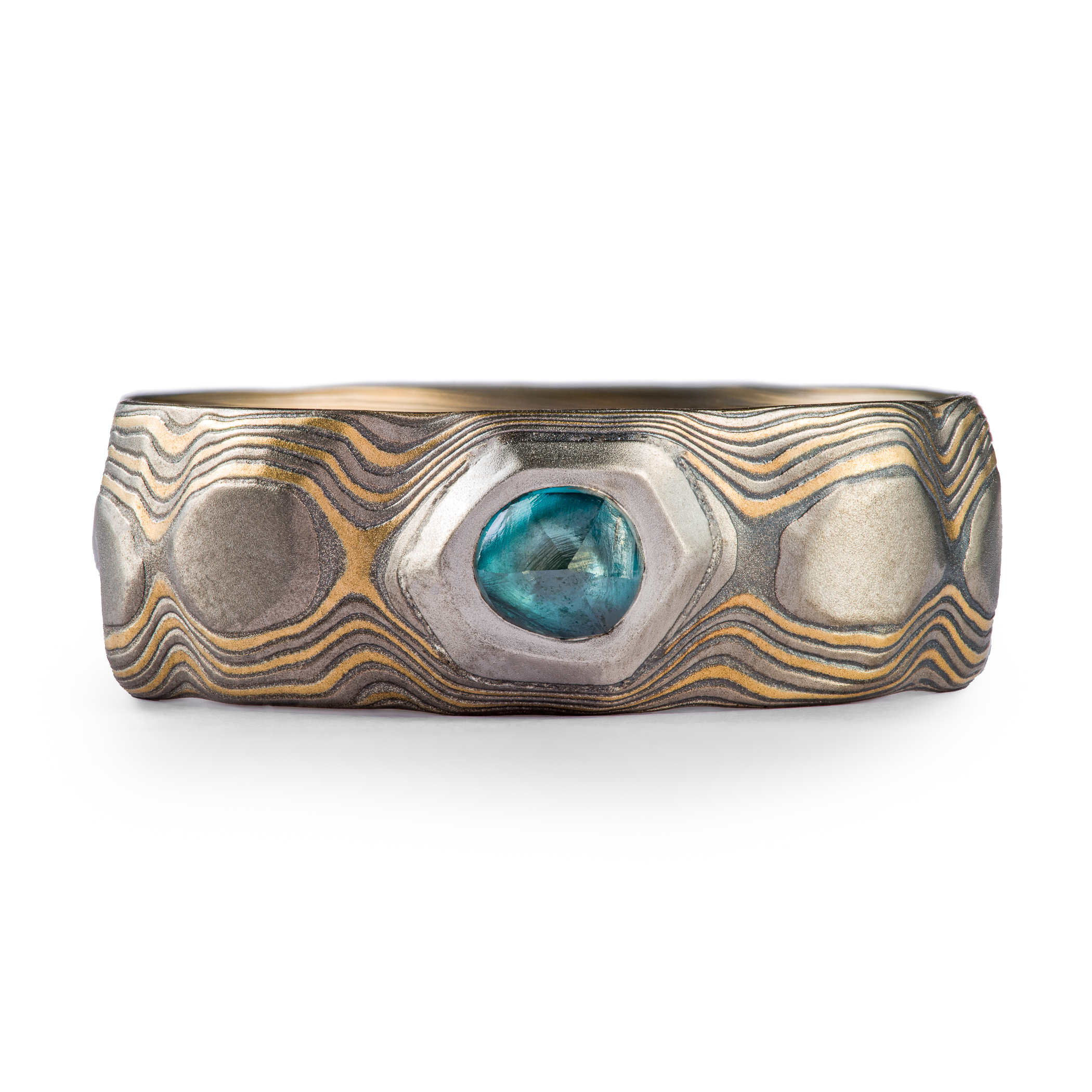 Wide men's style mokume gane ring carved to look like rocks, with a blue diamond crystal set into it, looking like it's emerging from the earth.