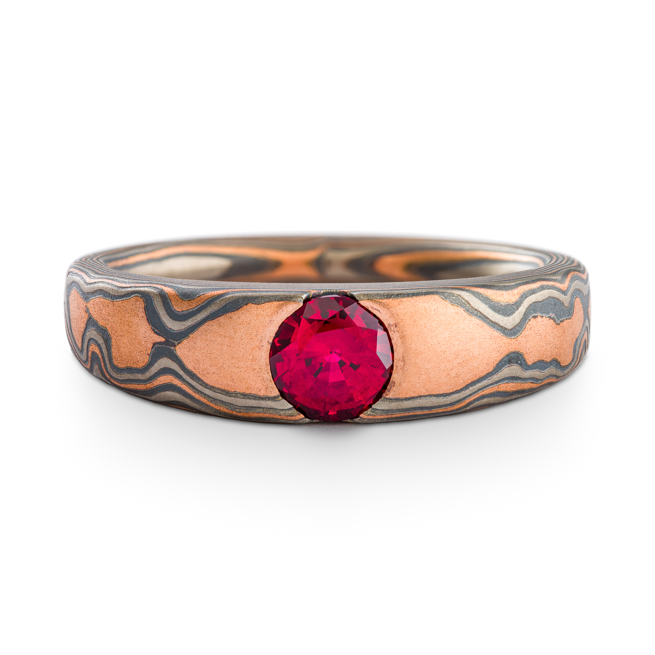 Tapered mokume gane patterned ring with a ruby in a cathedral setting. The ring is made with red gold, palladium and oxidized silver.