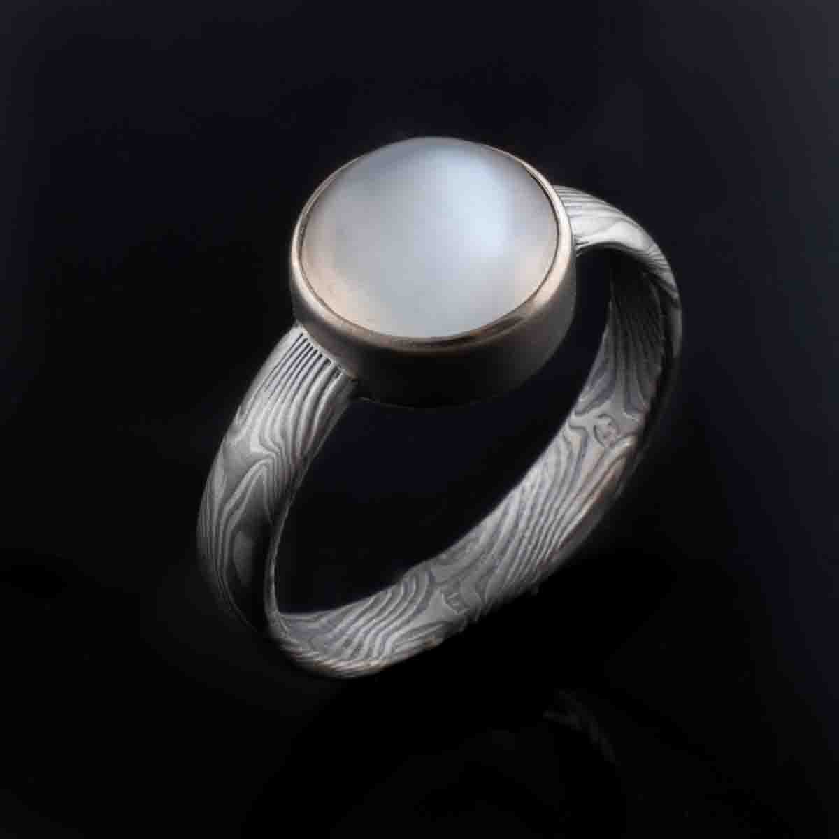 Mokume gane engagement ring with bezel set moonstone bezel setting. 14K white gold palladium sterling silver Beautiful artisan made handmade unique womens engagement ring light blue stone