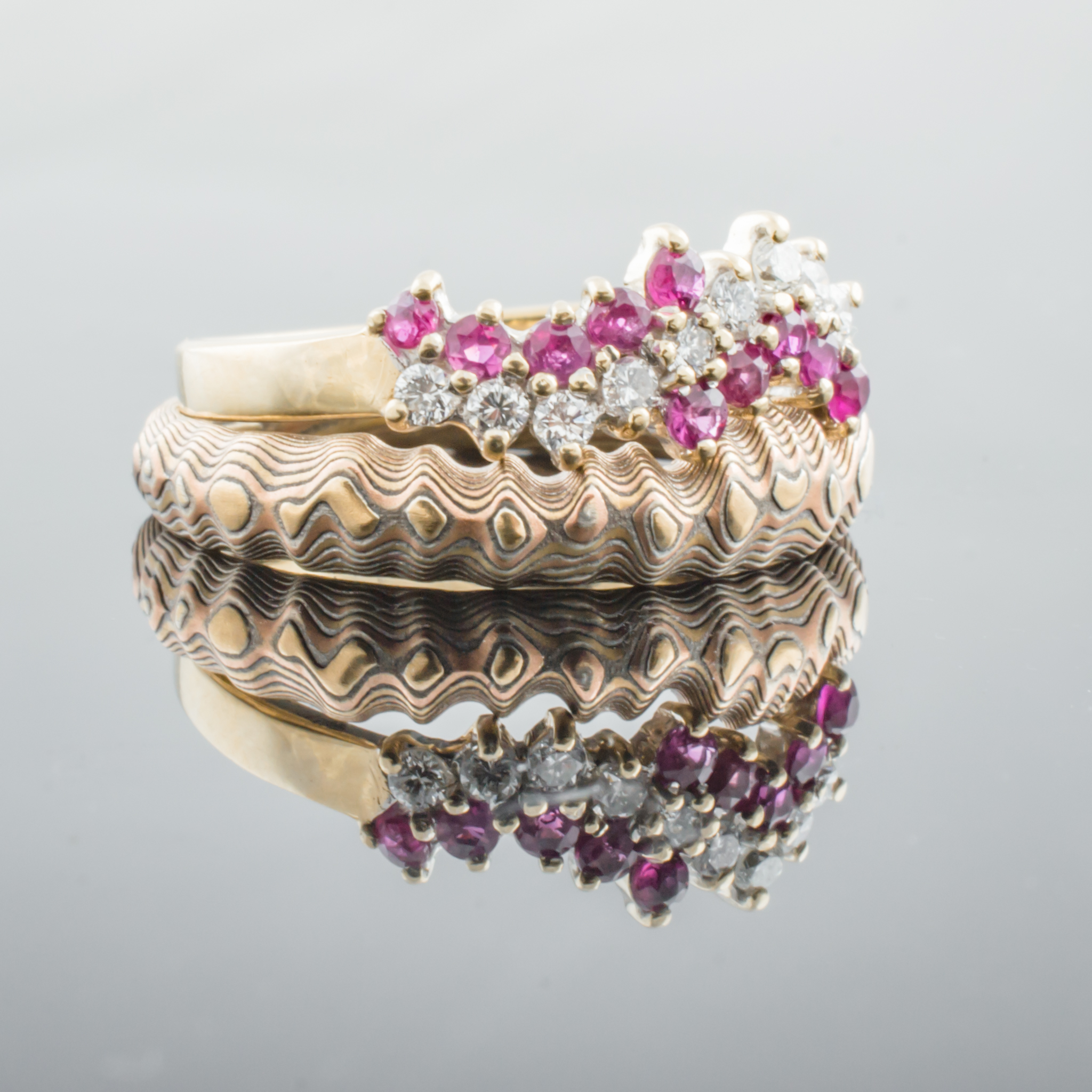 Uniquely contoured mokume gane ring with a shaped edge made to fit with an engagement ring, and textured to look like topography.