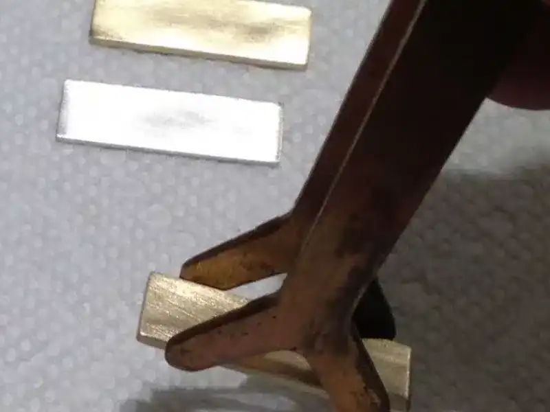 metal tongs holding mokume stock metal slivers