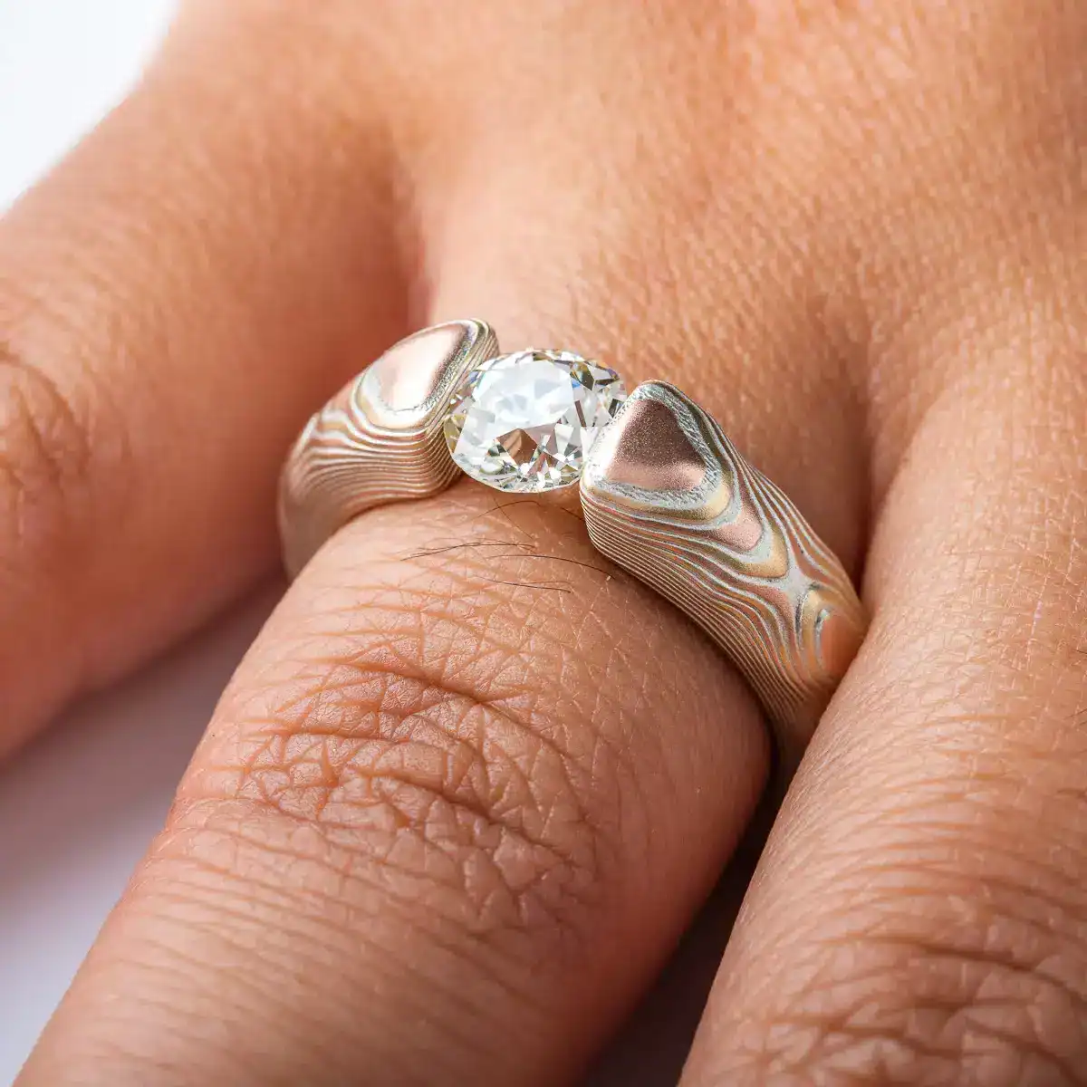 mokume gane tension set ring with diamond in guri bori pattern and gold and silver