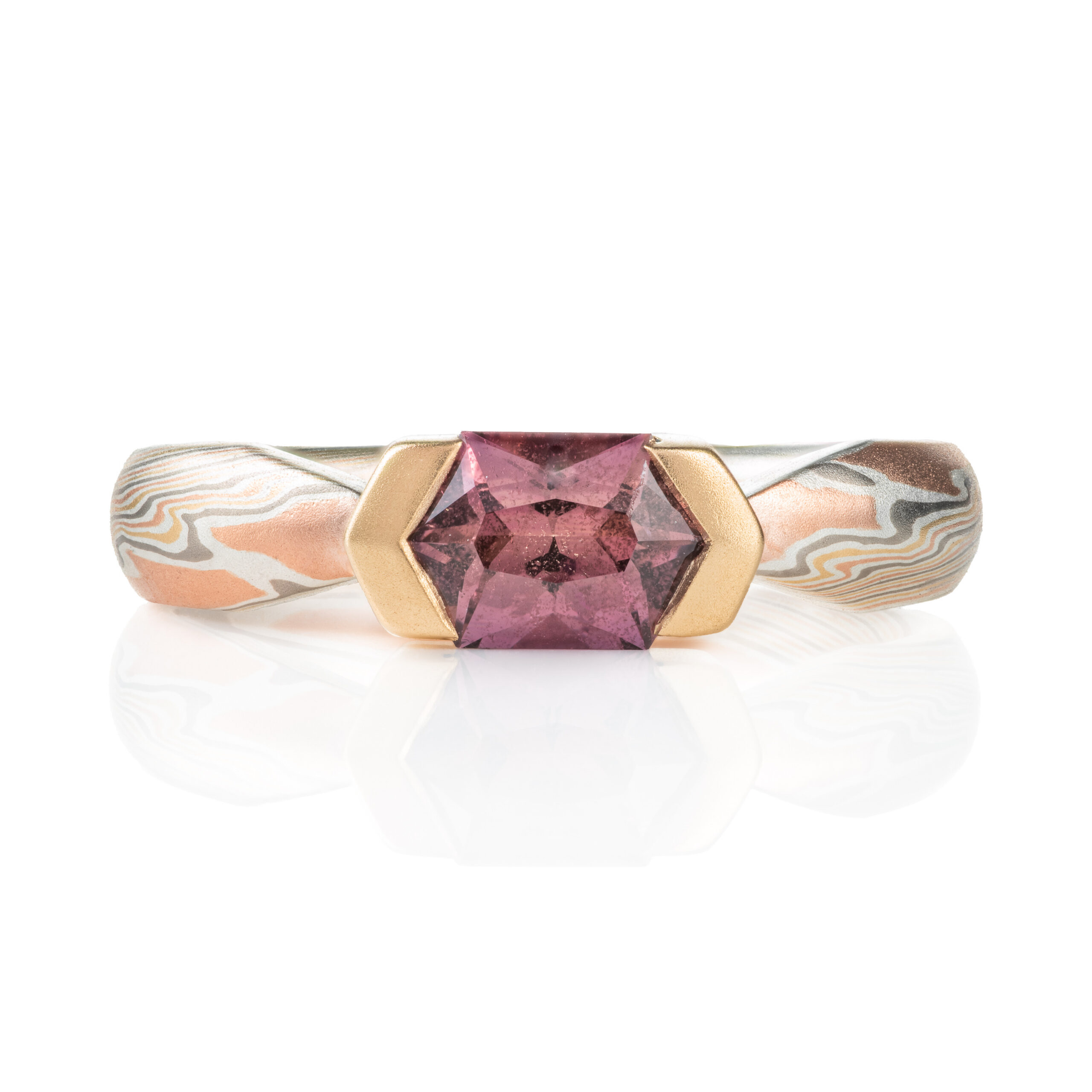 mokume gane whimsical engagement style ring with a unique hexagonal dusty rose sapphire in a partial bezel