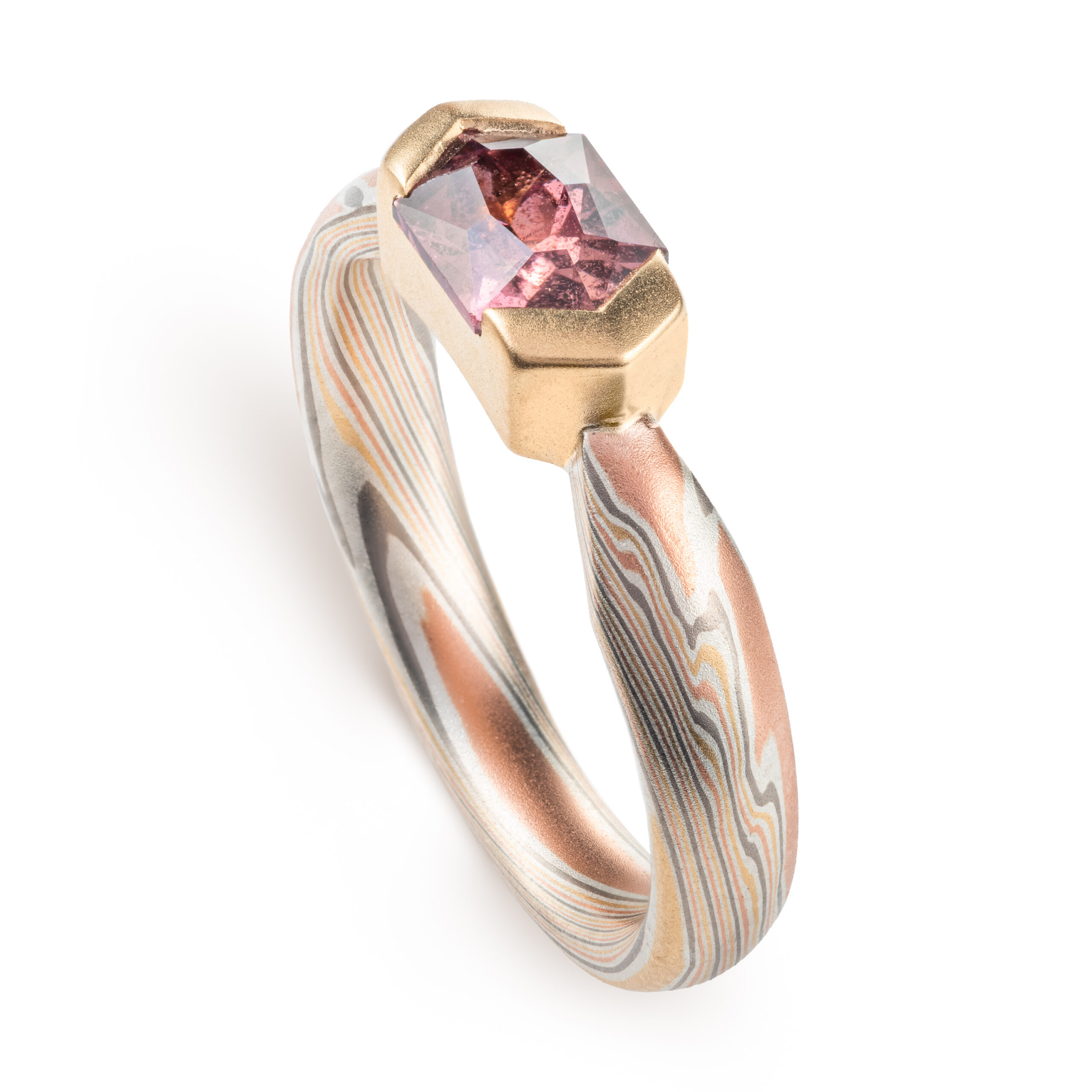 mokume gane whimsical engagement style ring with a unique hexagonal dusty rose sapphire in a partial bezel