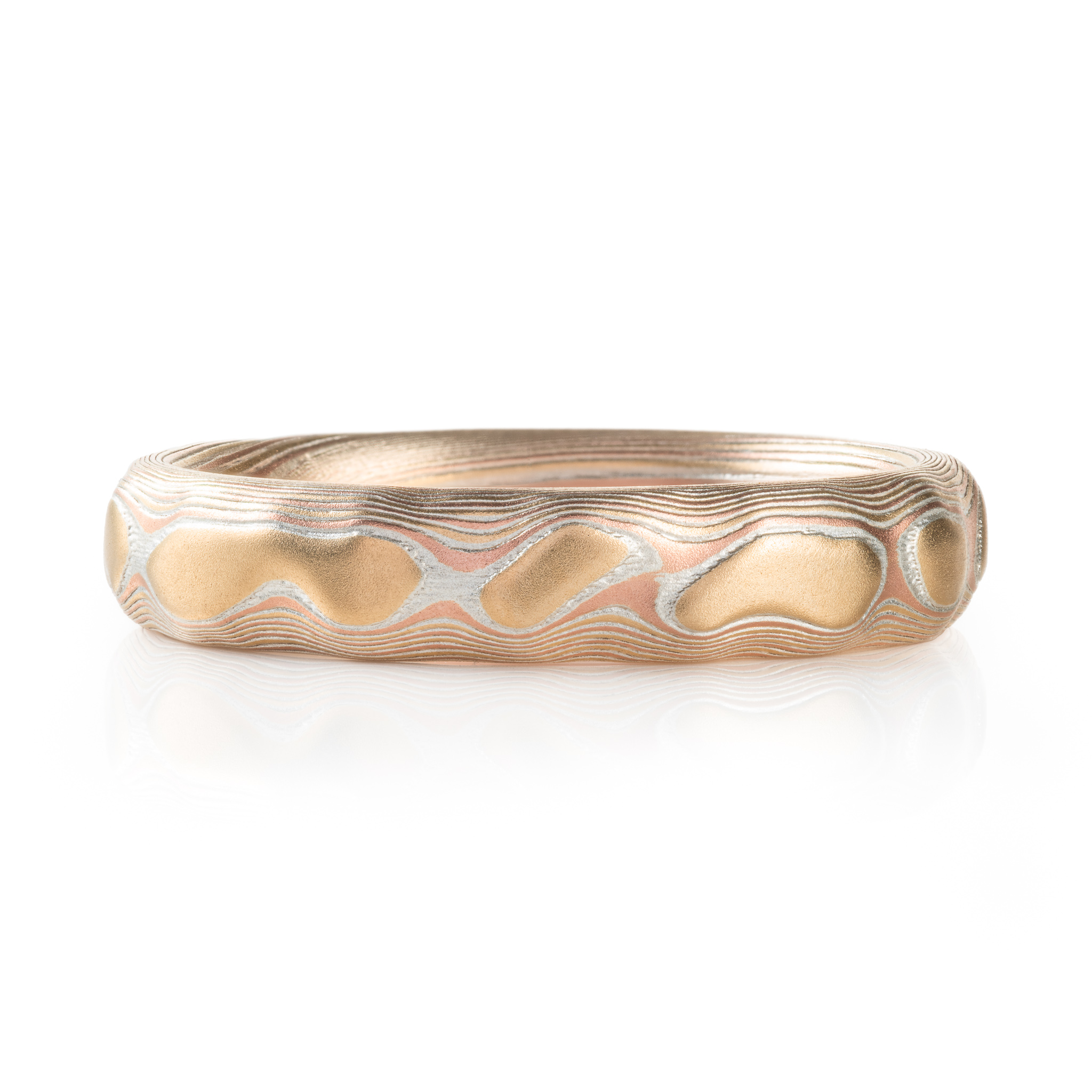 red gold, yellow gold and silver carved mokume ring. hand forged and hand carved. looks like gold islands floating above silver and red lines like a river of metal