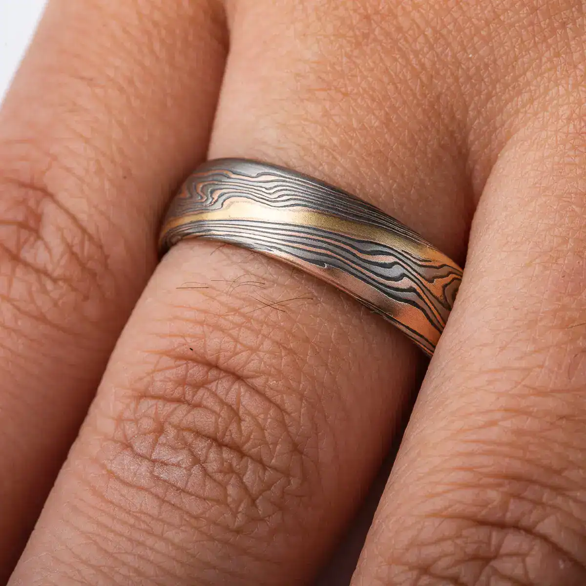 twisted mokume gane band patterned with an added gold stratum for contrast, main palette of the ring is red gold, palladium and oxidized silver
