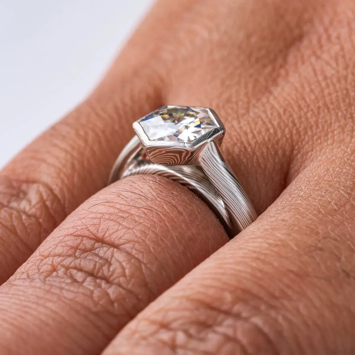 beautiful mokume gane ring with hexagon shaped moissanite in a floating mokume bezel with a light silvery palette