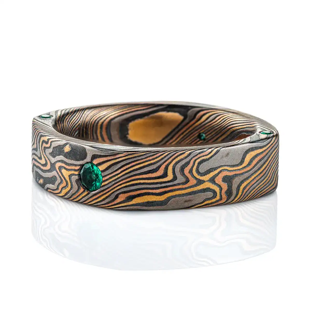 flat band made in soft square shape and rounded interior, made in mokume gane twist style pattern, with flush set small green stone