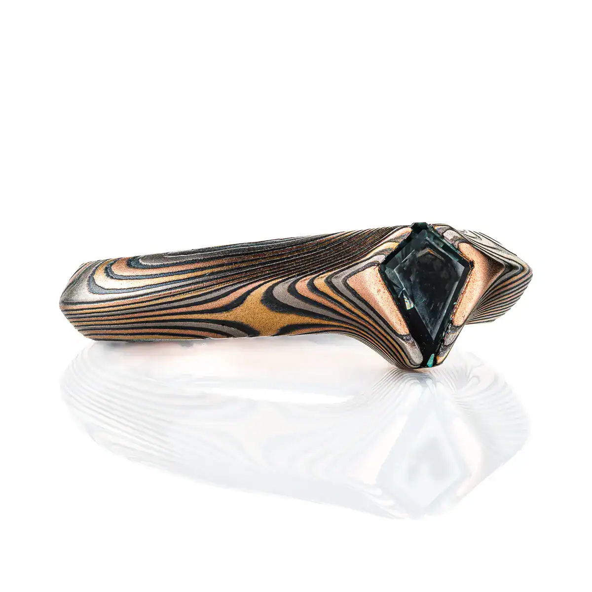 engagement style ring with beveled profile and a kite shaped stone with the point of the stone extending past the edge of the band