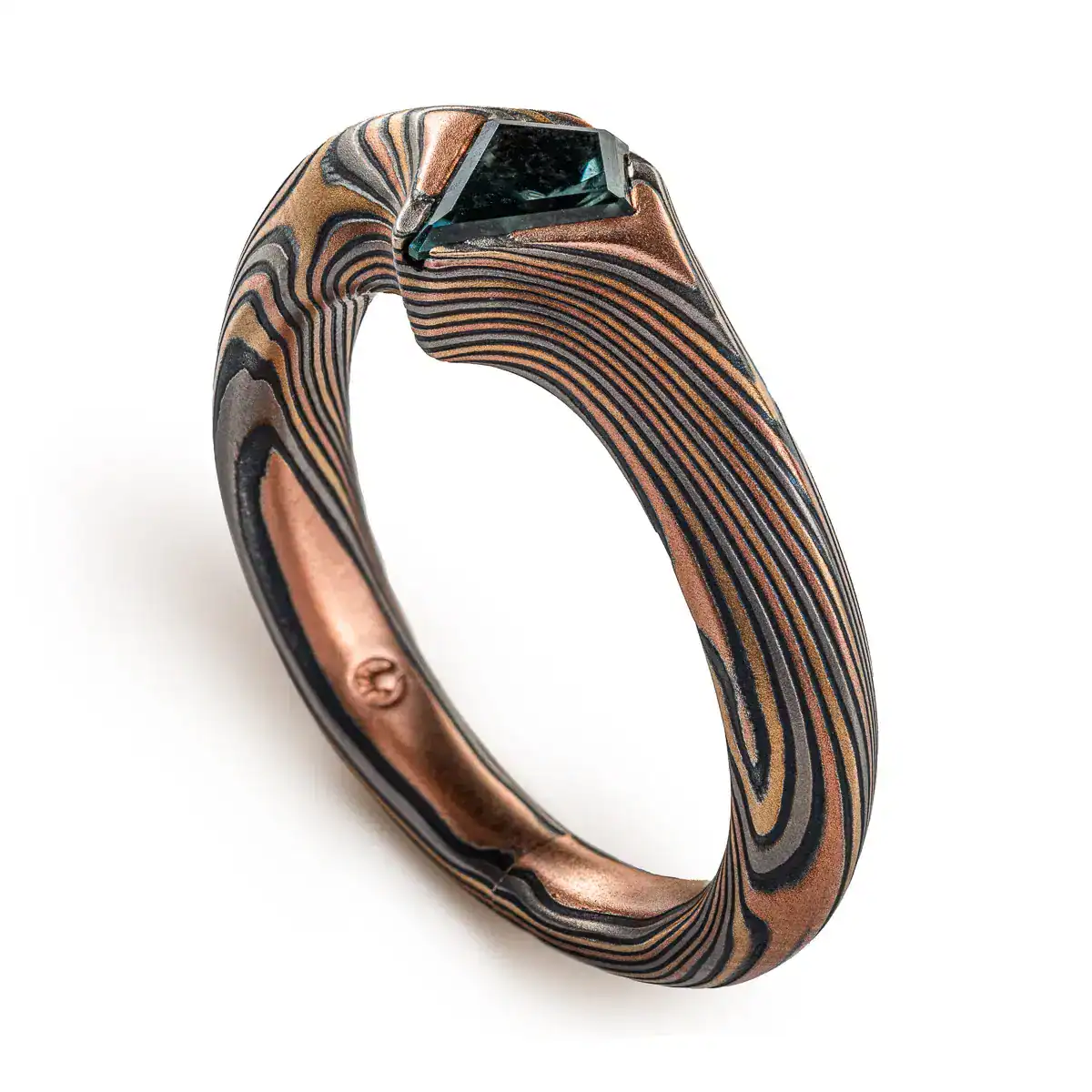 engagement style ring with beveled profile and a kite shaped stone with the point of the stone extending past the edge of the band