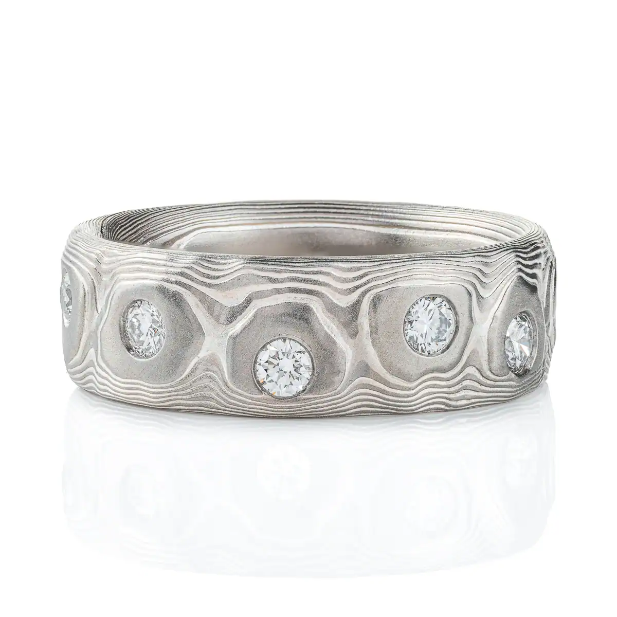 Wide men's style mokume gane band with flush set diamonds scattered around the entire ring for added sparkle. Ring is made in silver and palladium with a textured pattern resembling topography.