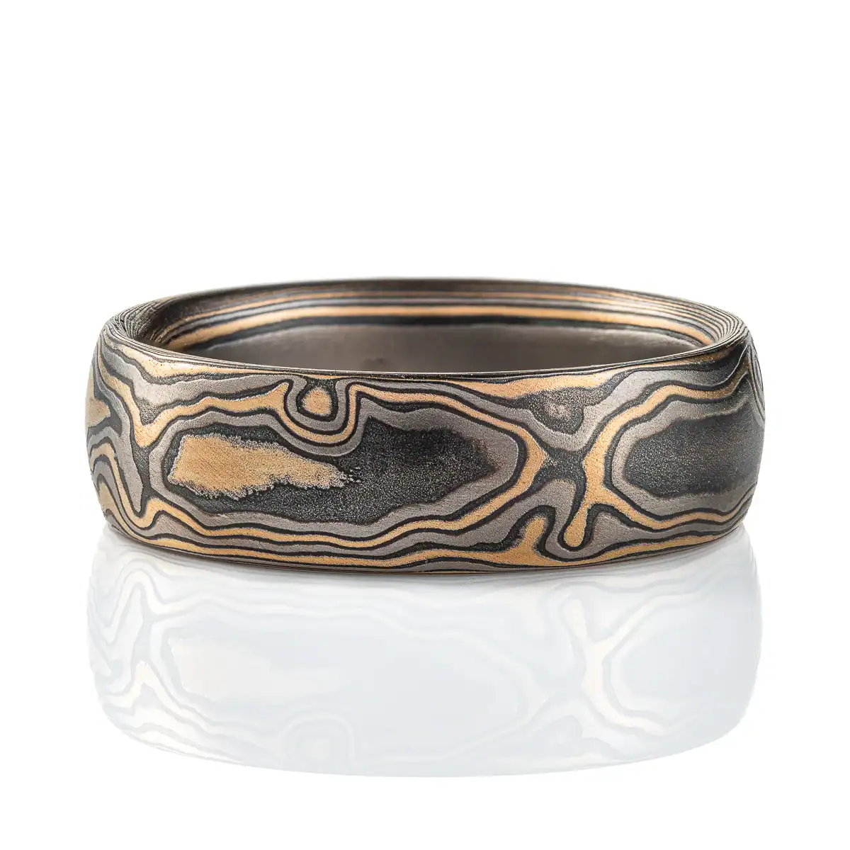 Gold and black mokume gane ring made in classic woodgrain pattern, metal colors used in the ring are yellow gold, palladium and oxidized silver (black in color). The ring has a low dome profile shape and slight texture from an etched finish.