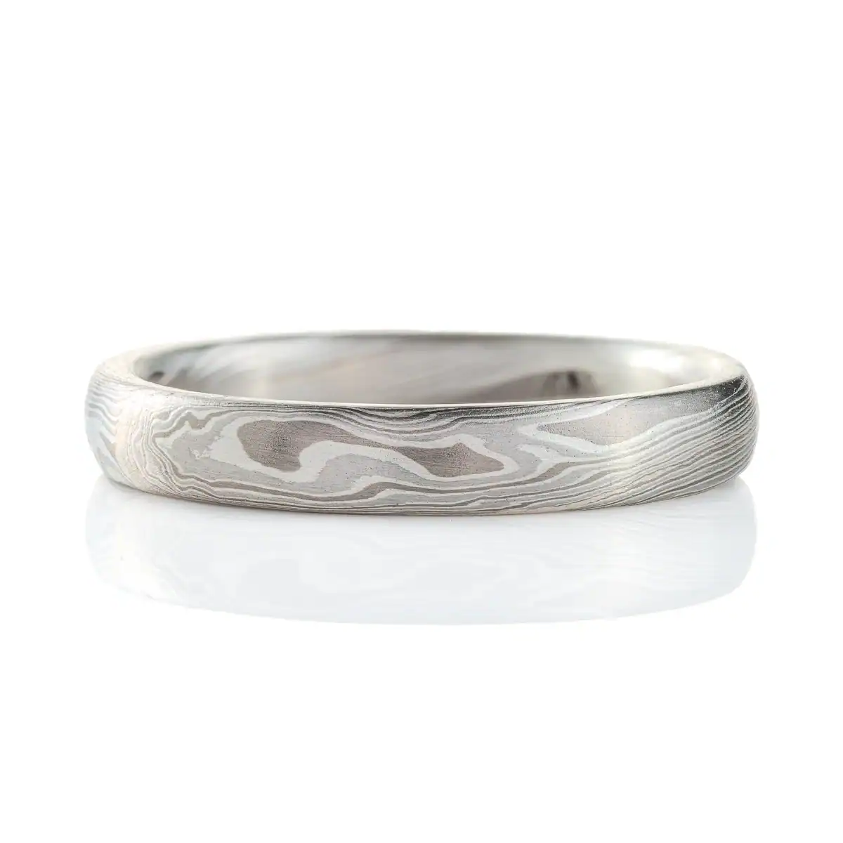 mokume gane band in silvery palette with different shades of gray, made in a twisting pattern and a smooth finish.