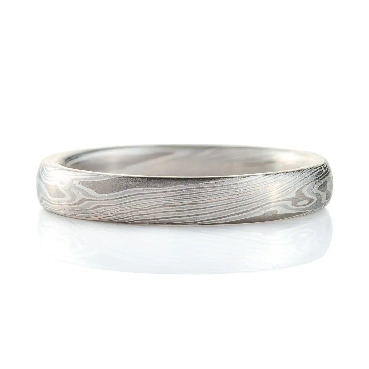 mokume gane band in silvery palette with different shades of gray, made in a twisting pattern and a smooth finish.