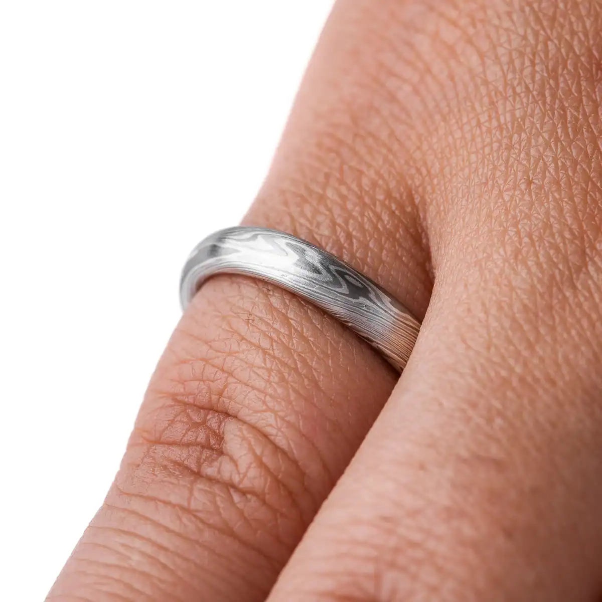 mokume gane band in silvery palette with different shades of gray, made in a twisting pattern and a smooth finish.