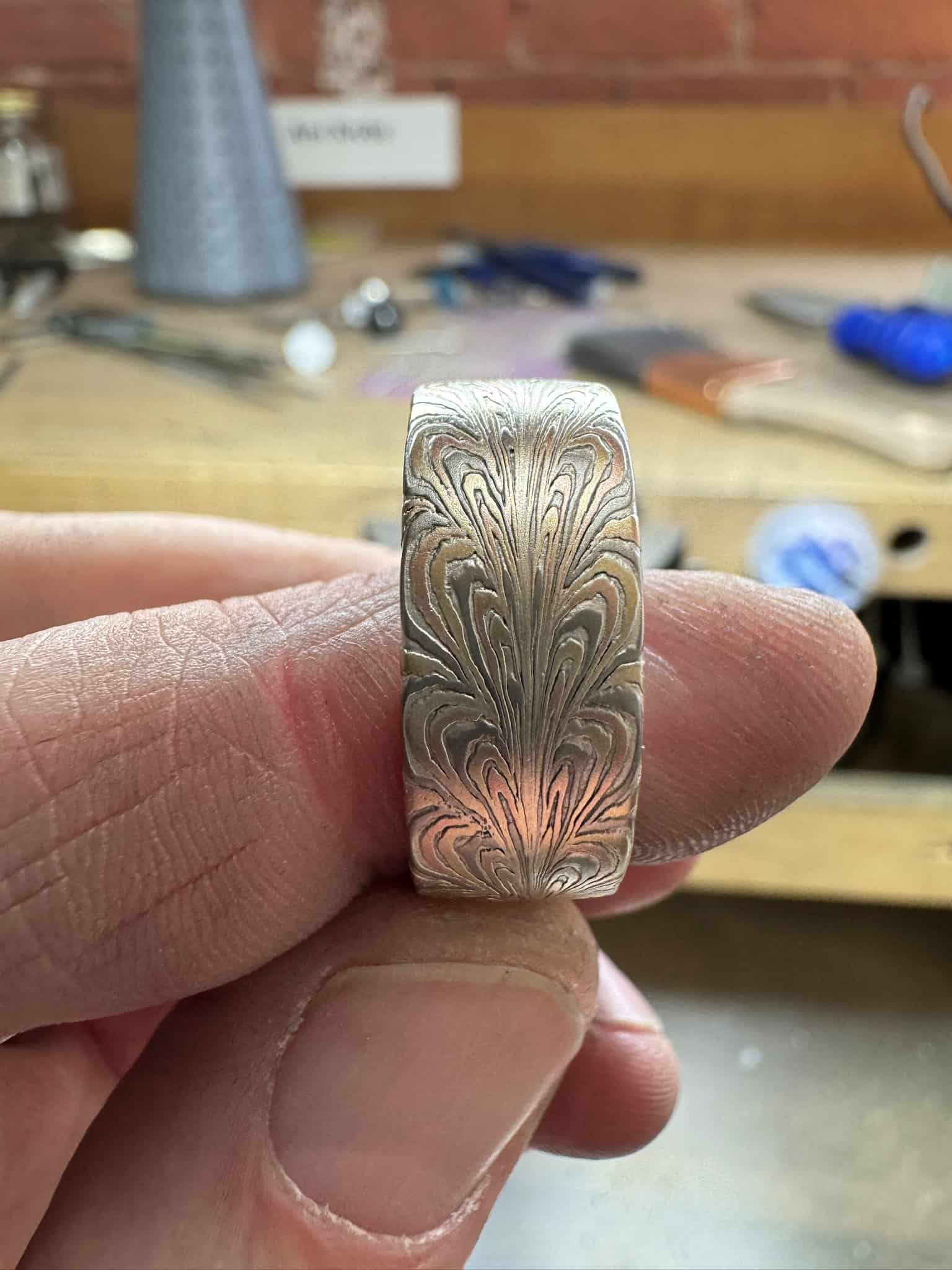 mokume gane and damascus technique used to create a patterned ring inspired by the shape of a feather