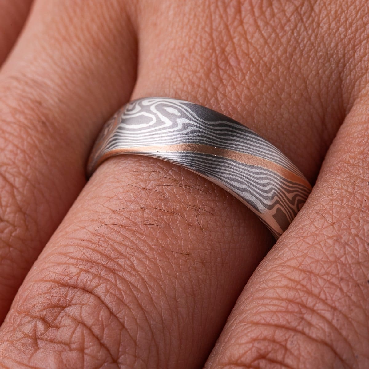 Silvery mokume gane ring made in twisting pattern, with one streak of red gold running through.