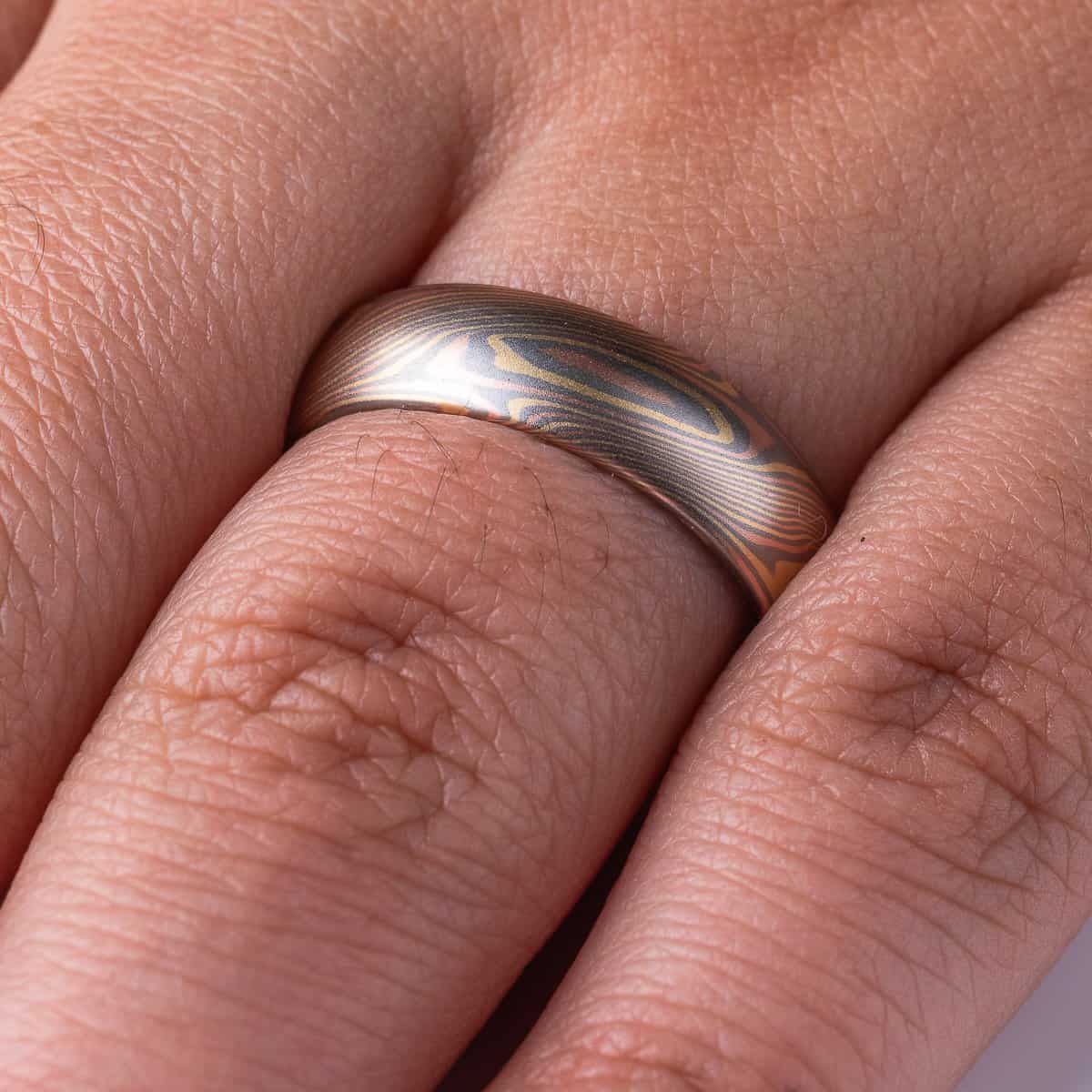 Slim mokume gane patterned ring with angled ellipse shapes running around the band, made with red gold, yellow gold and palladium, domed profile, smooth finish.