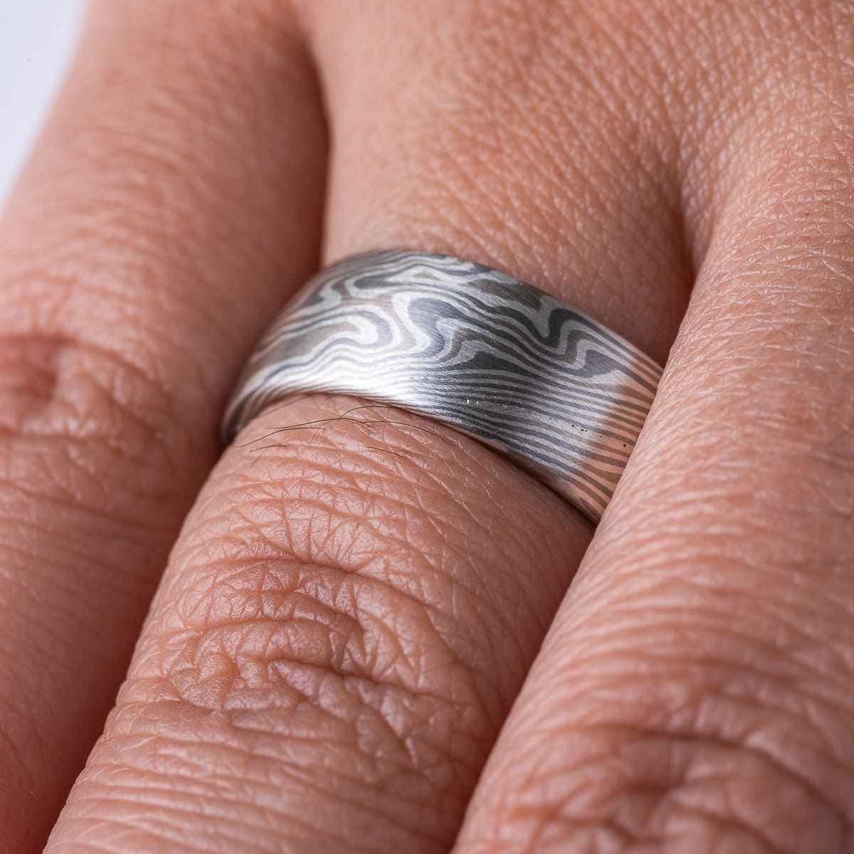 Wide, smooth finish mokume gane patterned ring, made with three different metal colors, ranging from light to dark gray.