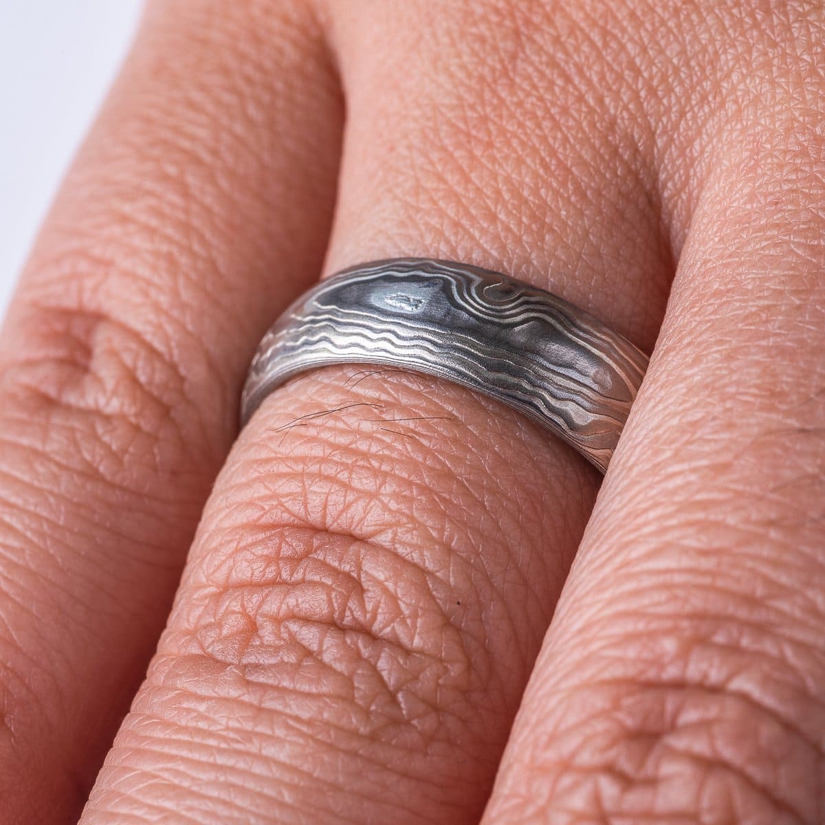Very textured woodgrain patterned mokume gane band, made of different layers of shades of gray. Texture resembles rippling water.