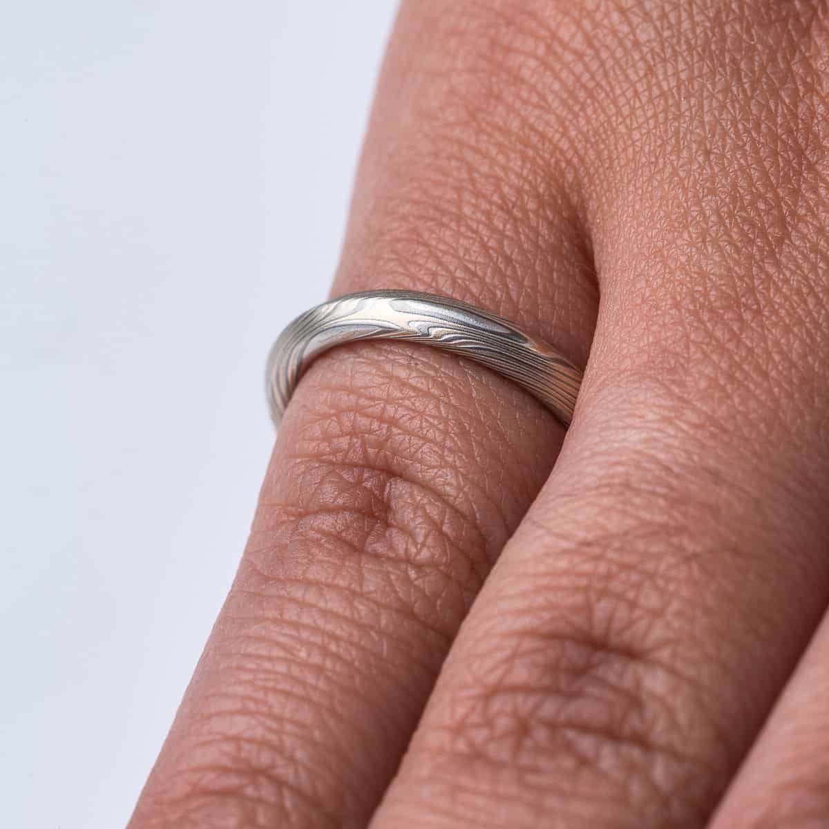 Mokume gane ring with beveled profile, patterned in long swooping lines and starburst like arcs. Made with yellow gold, silver and palladium.