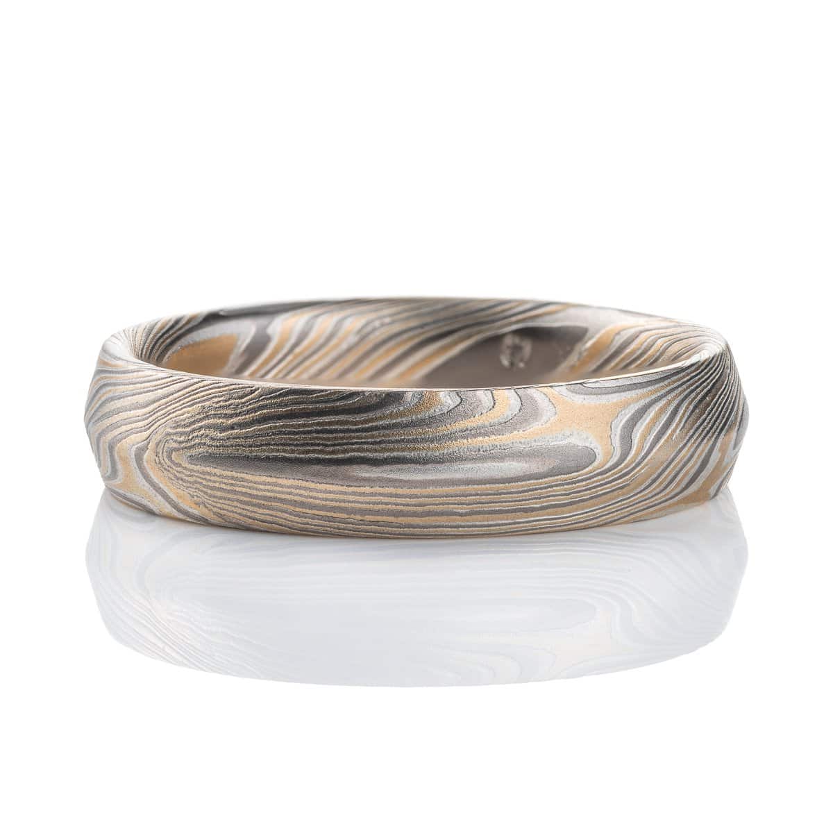 Mokume gane ring with beveled profile, patterned in long swooping lines and starburst like arcs. Made with yellow gold, silver and palladium.