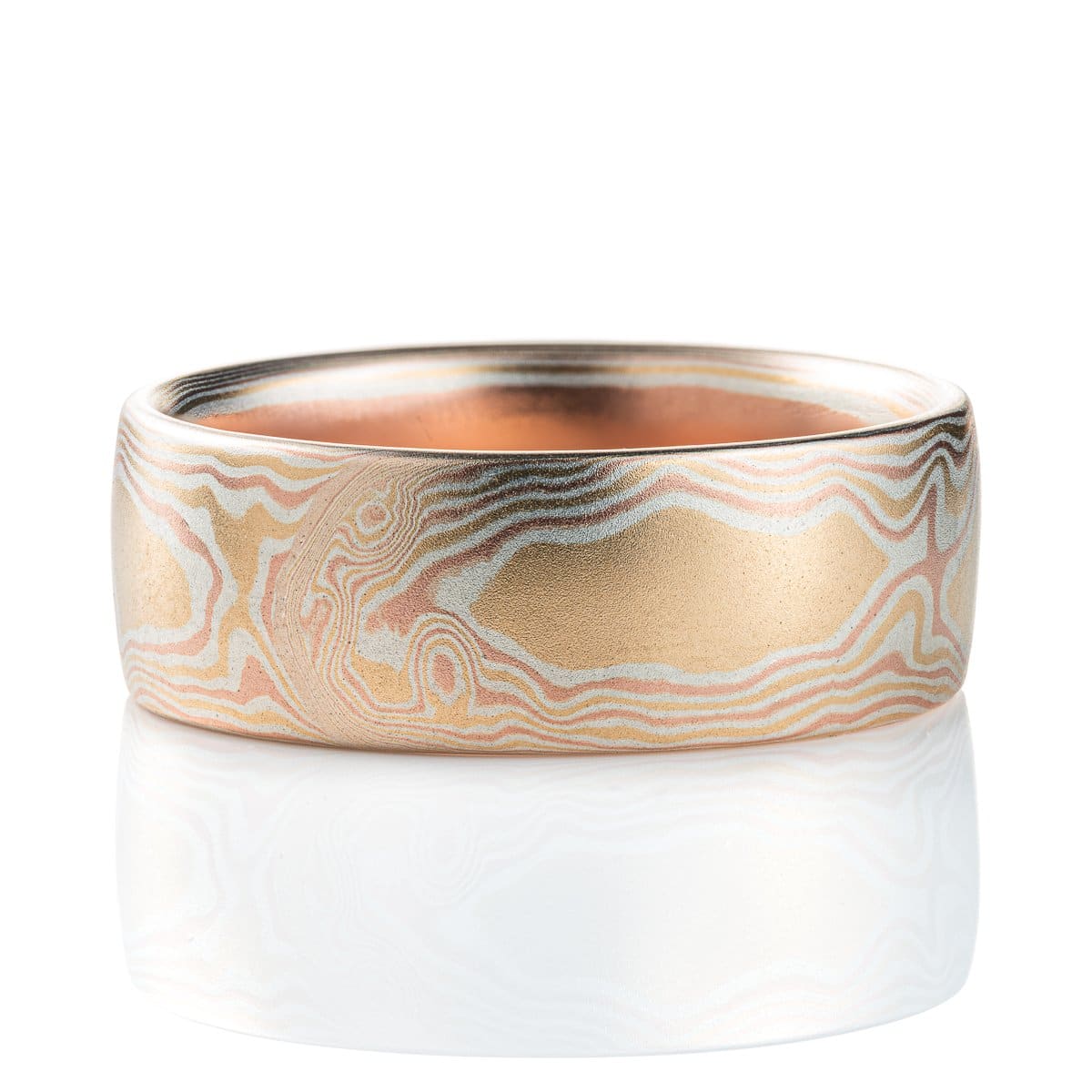 Warm toned mokume gane ring patterned to look like woodgrain. Made with layers of red gold, yellow gold and silver, with a smooth finish.