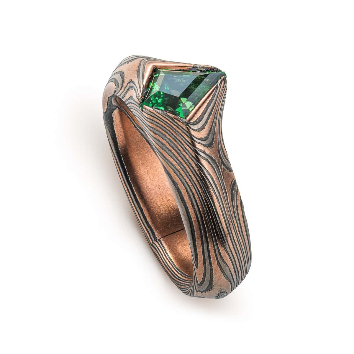 Statement mokume gane ring made with red gold, palladium and oxidized silver, with a bright green kite shaped stone, the band wraps around the long point of the stone.
