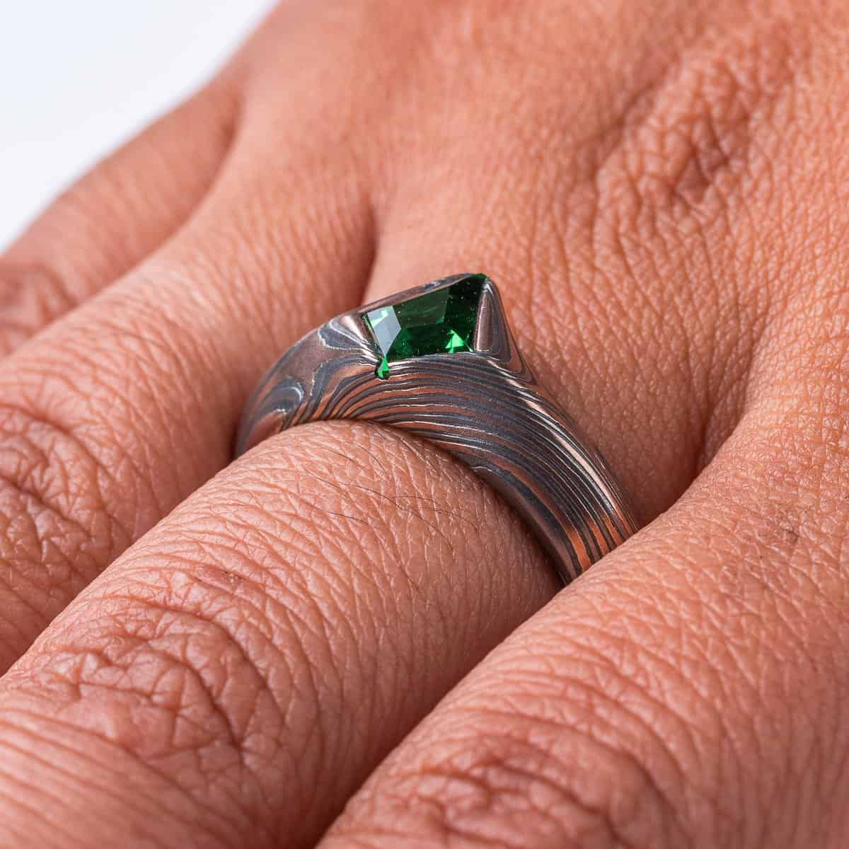 Statement mokume gane ring made with red gold, palladium and oxidized silver, with a bright green kite shaped stone, the band wraps around the long point of the stone.