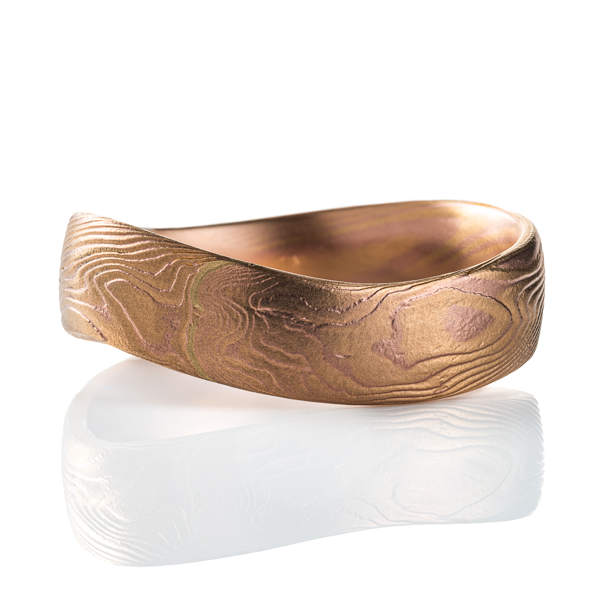 Mokume gane patterned ring with an undulating shape, made with red and yellow gold.