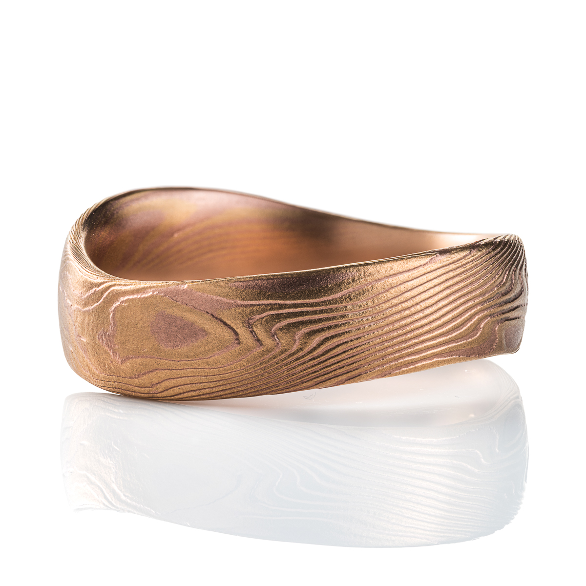 Mokume gane patterned ring with an undulating shape, made with red and yellow gold.