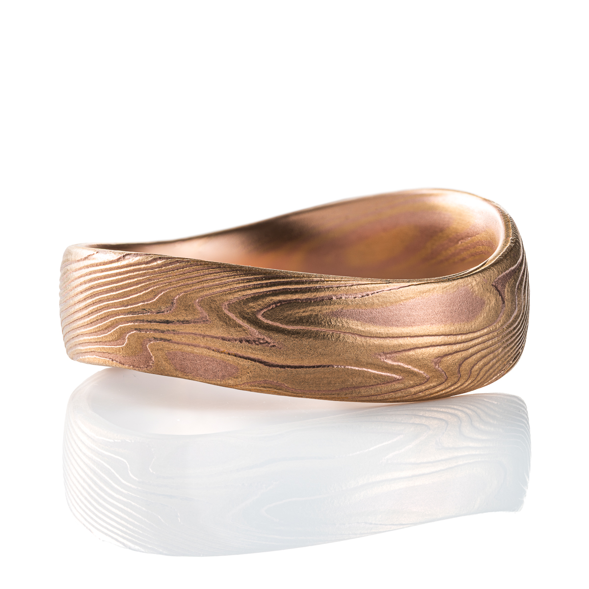 Mokume gane patterned ring with an undulating shape, made with red and yellow gold.