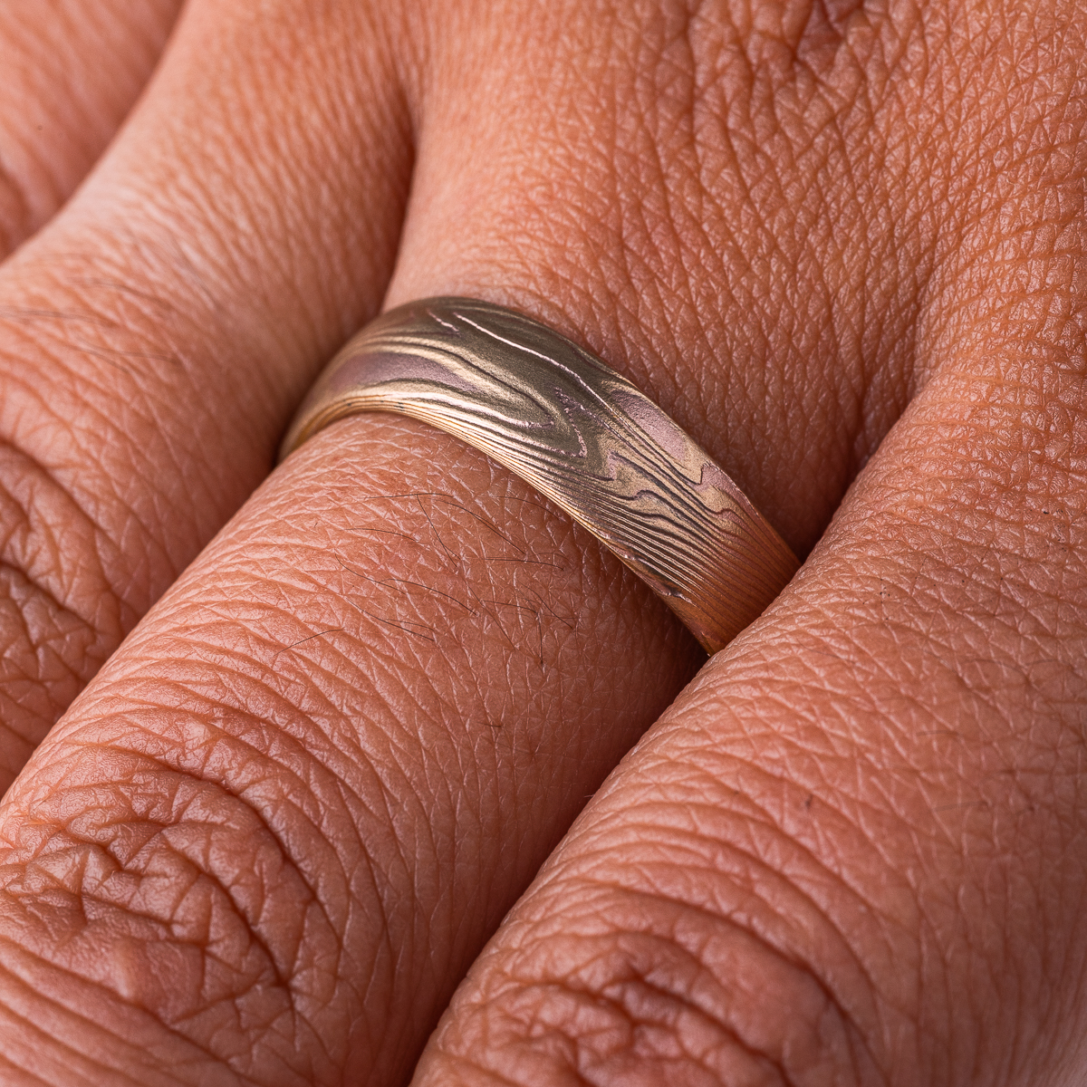Mokume gane patterned ring with an undulating shape, made with red and yellow gold.