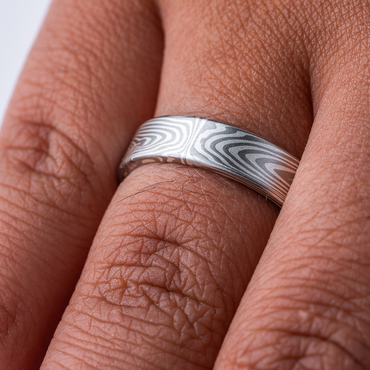 Narrow, flat profile band, mokume gane pattern in a linear style, made with palladium and silver for an overall silvery/gray color palette.