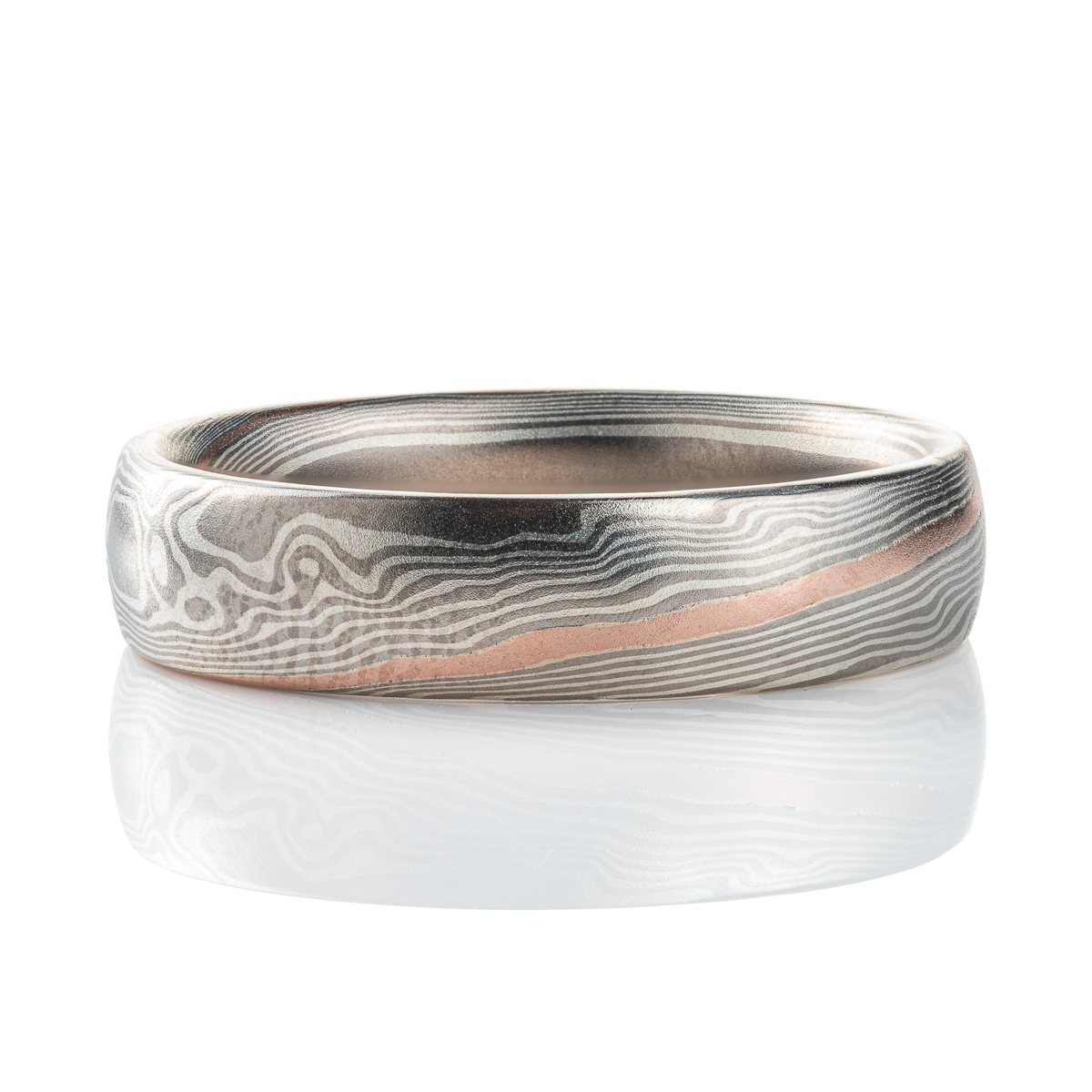 Smooth, domed, slender band patterned in mokume gane twist style, most of the ring is made in silver and palladium, with one stripe of red gold.