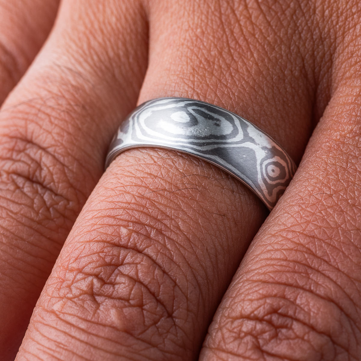 Smooth, domed ring, made in a mokume gane woodgrain pattern, in a combination of palladium and sterling silver.