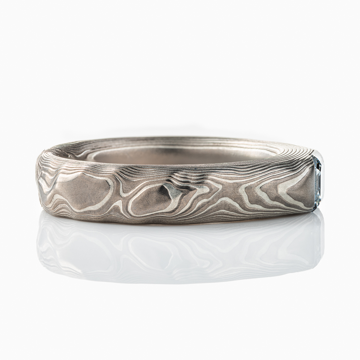 Textured mokume gane patterned ring, with three dimensional carving made to resemble rock. The ring is slightly thicker towards the top, to hold an asscher cut diamond that has been set flush into the ring.