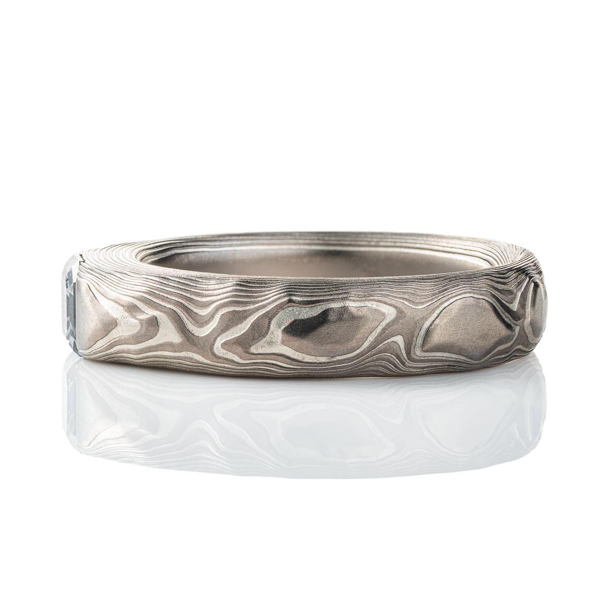 Textured mokume gane patterned ring, with three dimensional carving made to resemble rock. The ring is slightly thicker towards the top, to hold an asscher cut diamond that has been set flush into the ring.