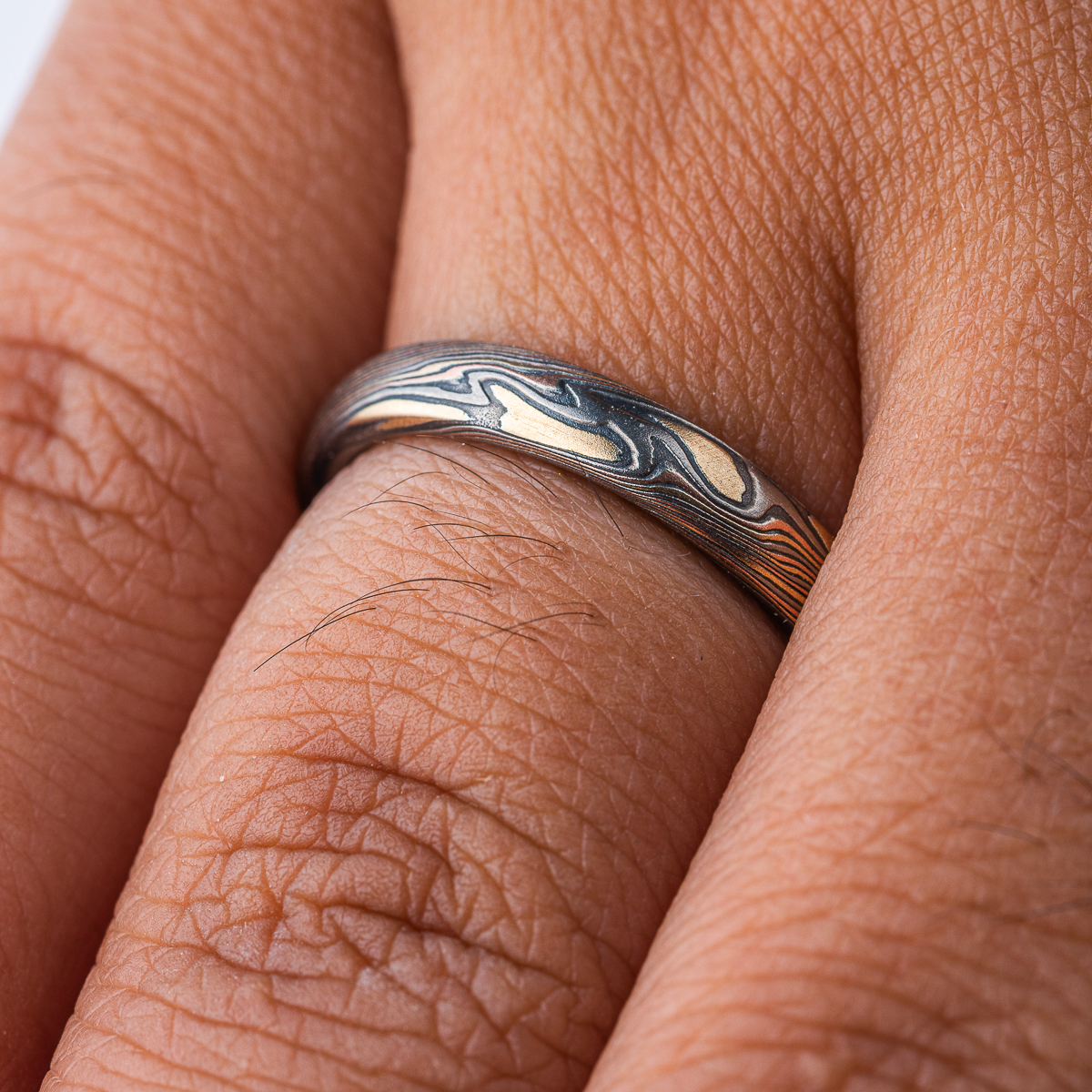 Narrow mokume gane patterned band, made with red gold, yellow gold, palladium and oxidized silver.