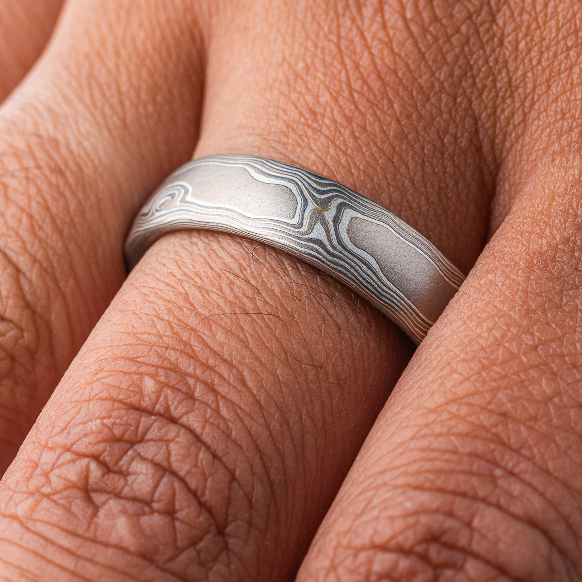 Mokume gane gray toned band, made to resemble woodgrain. Smooth surface, made with white gold, palladium and silver.