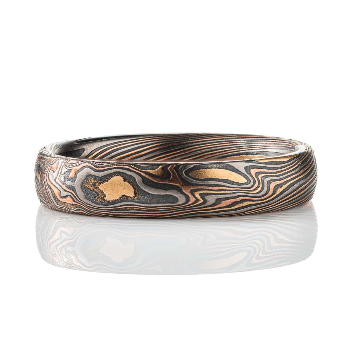 Mokume gane patterned band, made to look like woodgrain, made of layers of red gold, yellow gold, palladium, and oxidized silver.