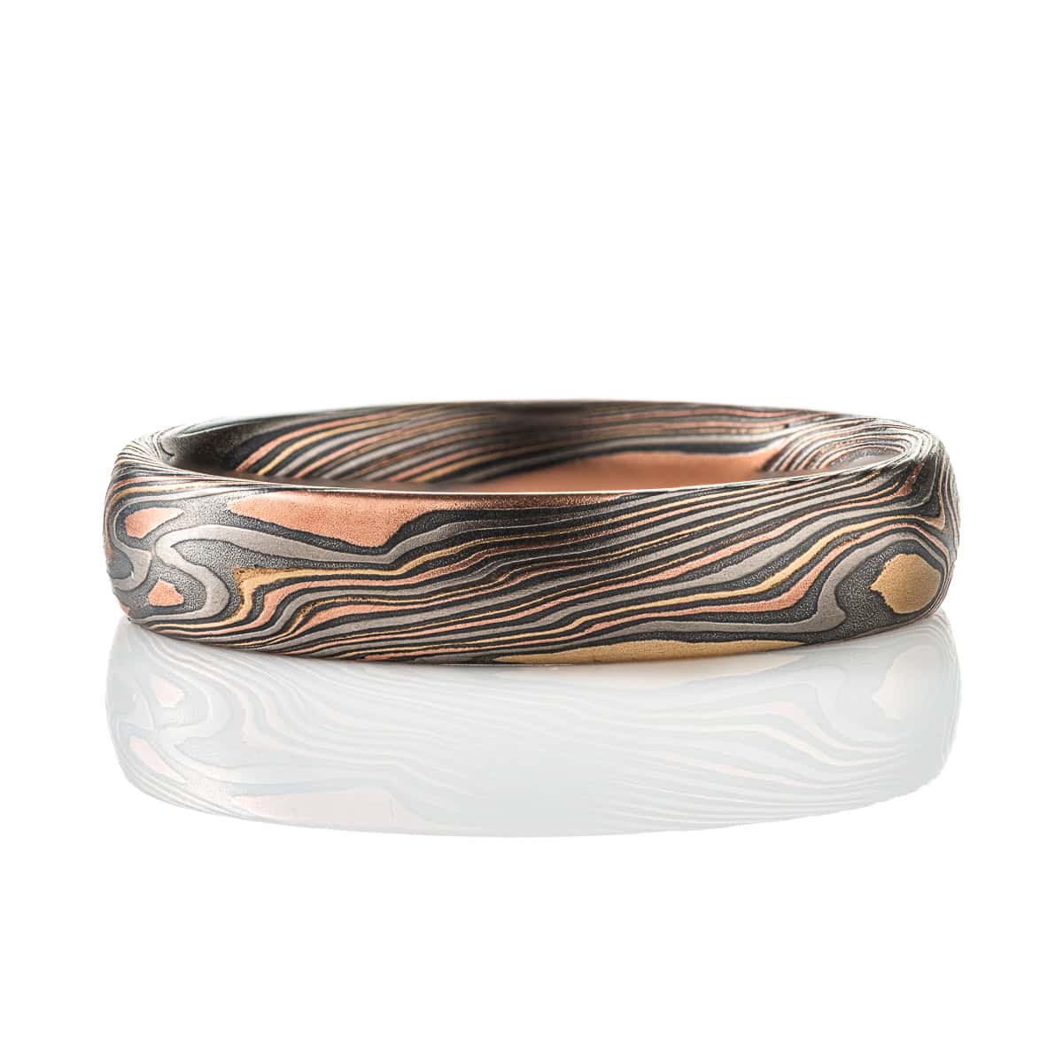 Mokume gane patterned band, made to look like woodgrain, made of layers of red gold, yellow gold, palladium, and oxidized silver.
