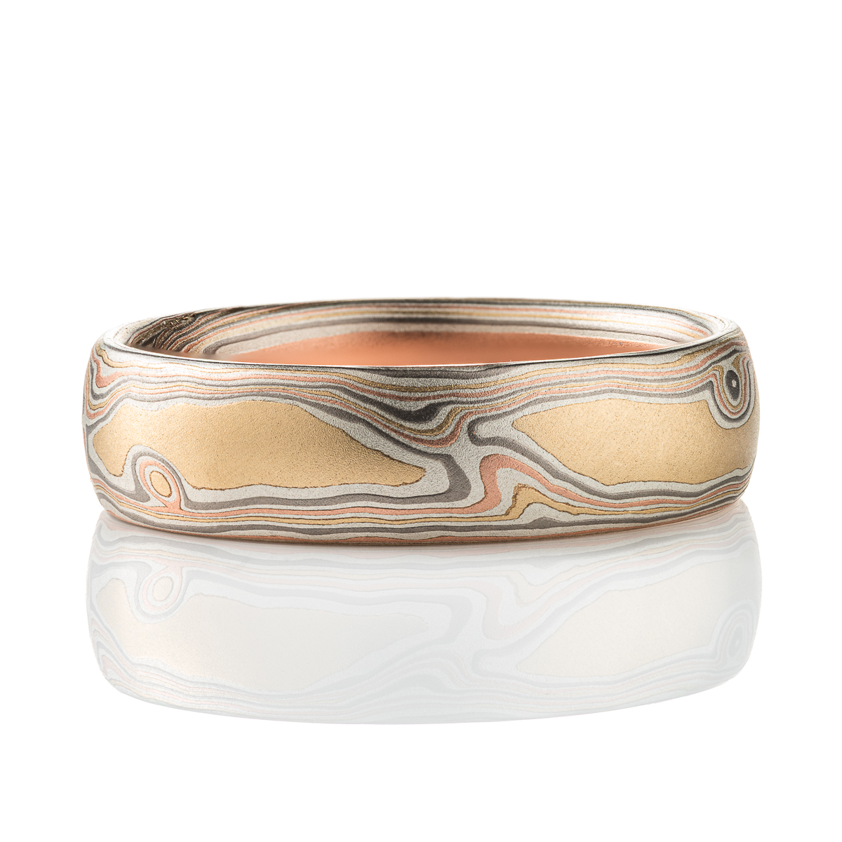 Slim mokume gane patterned band, twisting and organic flowing pattern, made with layers of red gold, yellow gold, palladium, and oxidized silver.