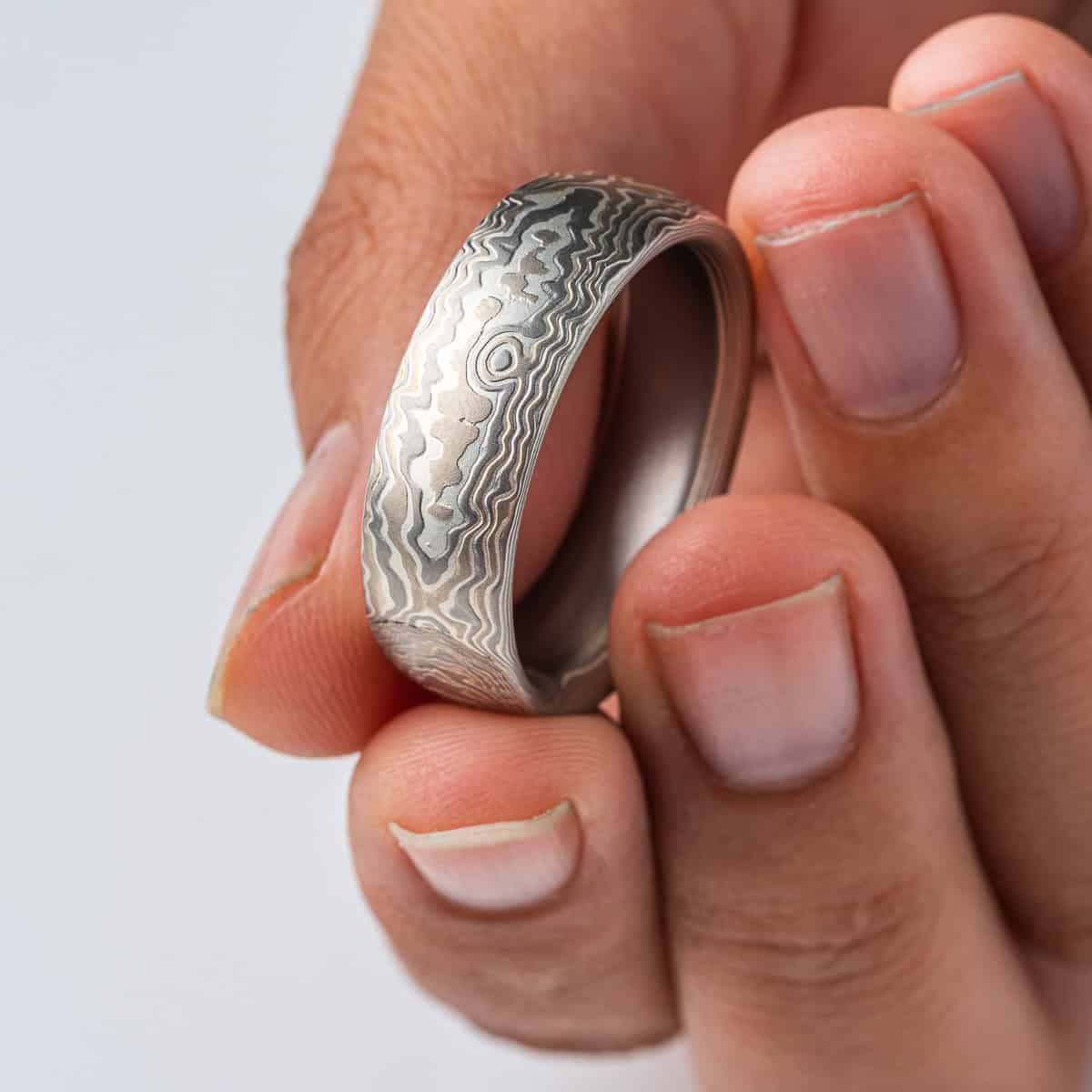 Wide, large mokume gane men's ring, patterned to look like carved woodgrain. Made with layers of white gold, palladium and silver, with an etched finish for texture.
