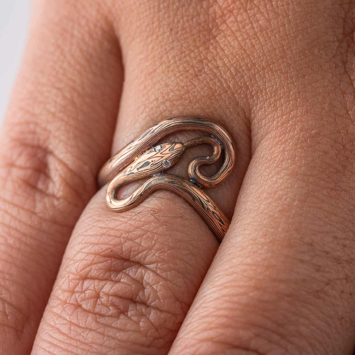 Custom handcrafted and forged mokume gane ring made to look like a snake curling and twisting around the finger. Made with red gold and oxidized silver, with tiny diamonds as eyes.