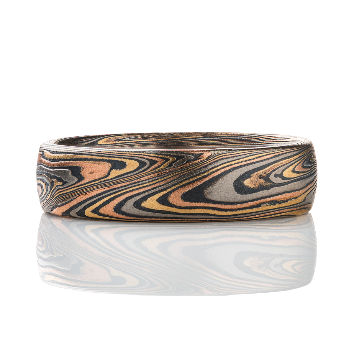krikawa Patterned mokume gane men’s ring, made with red gold, yellow gold, palladium and oxidized silver. The pattern is organic feeling, swirling, sweeping lines.