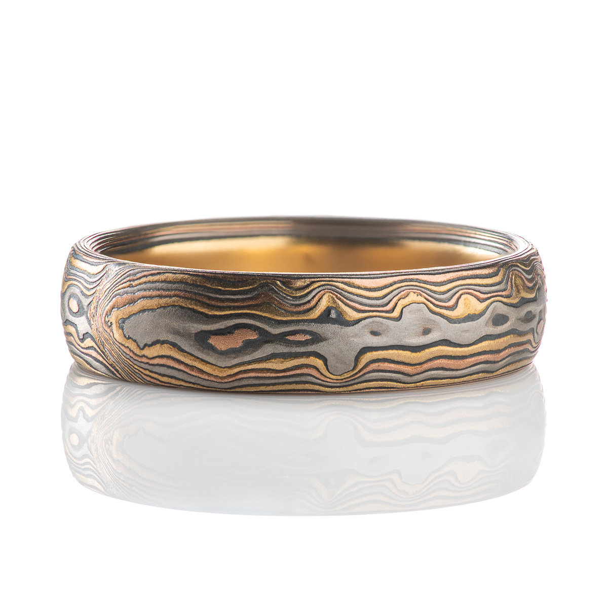 Custom made and patterned mokume gane ring, made with a four metal combination of red gold, yellow gold, palladium and oxidized silver. The pattern is organic, made to resemble woodgrain and natural textures.