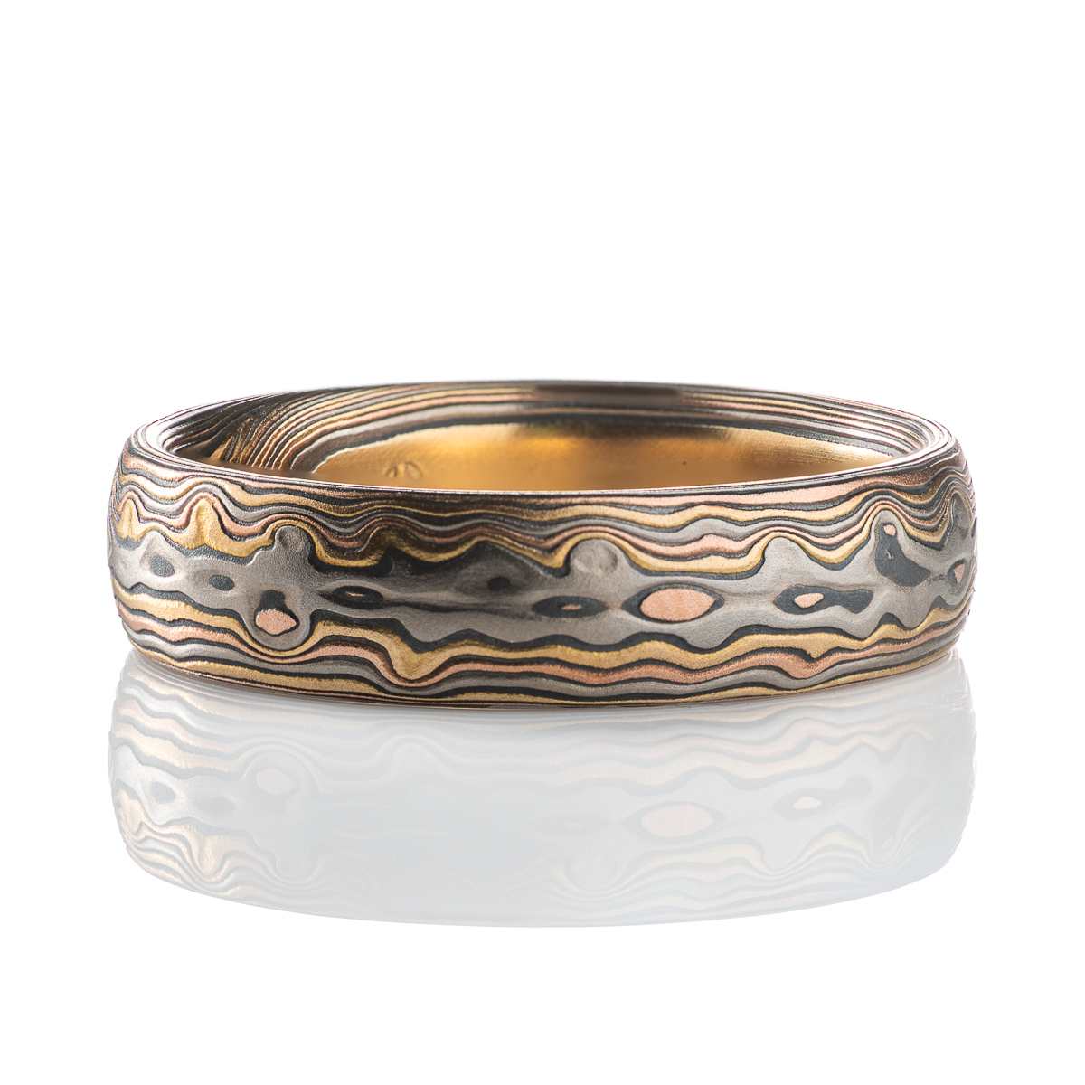 Custom made and patterned mokume gane ring, made with a four metal combination of red gold, yellow gold, palladium and oxidized silver. The pattern is organic, made to resemble woodgrain and natural textures.