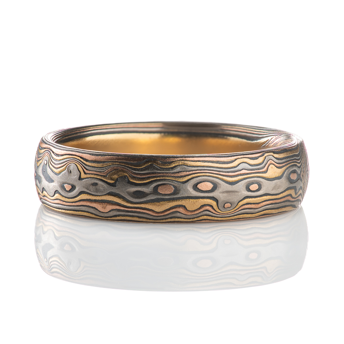 Custom made and patterned mokume gane ring, made with a four metal combination of red gold, yellow gold, palladium and oxidized silver. The pattern is organic, made to resemble woodgrain and natural textures.